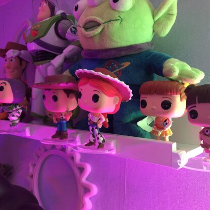 Étagère blanche garnie de POP Toy Story sous un éclairage coloré